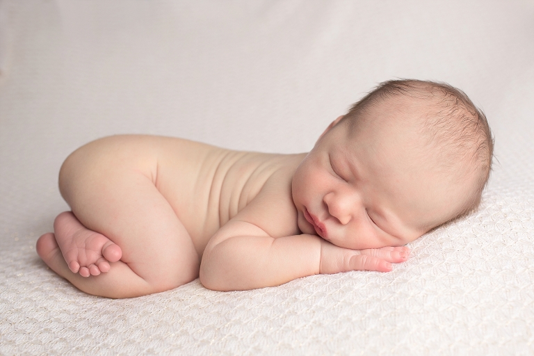 Newborn baby sleeping on cream blanket